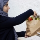 Muslimische junge Frau übergibt Lebensmitteltüte an Bedürftige, MEA Muslimische Ehrenamtsagentur Infoveranstaltung April